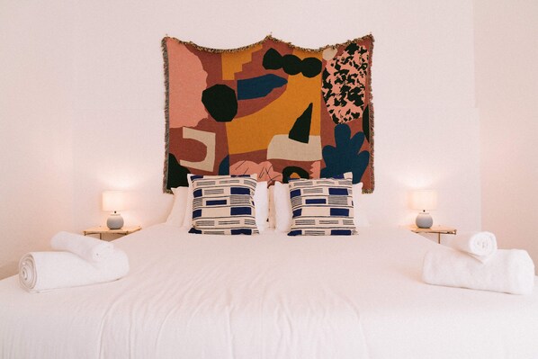 A neatly made bed with white linens, two decorative pillows, and two bedside lamps. - Outsite Puerto Rico - San Juan - Work, Connect, Explore (San Juan)