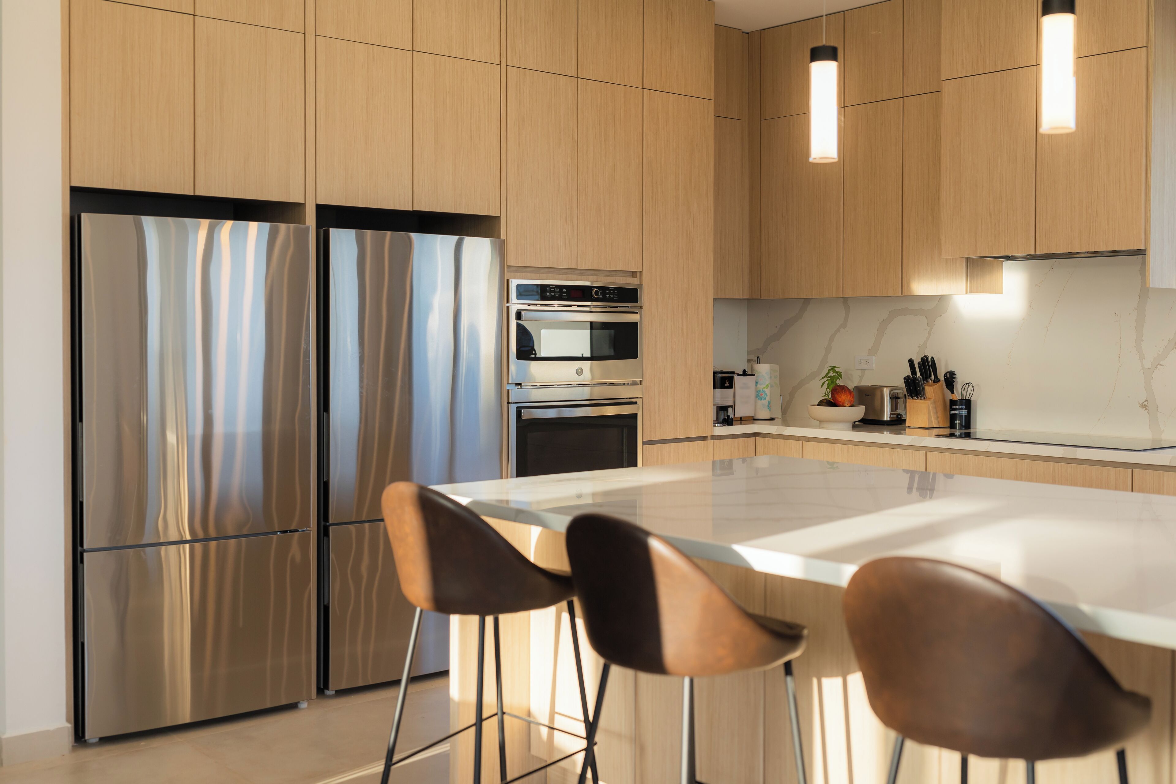A modern kitchen with stainless steel appliances, wooden cabinets, and a marble countertop.