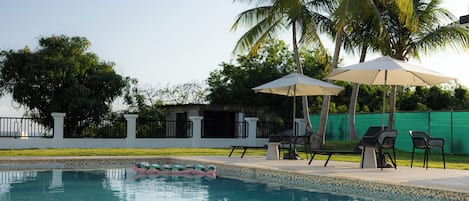 Una piscina al aire libre, sombrillas, sillones reclinables de piscina