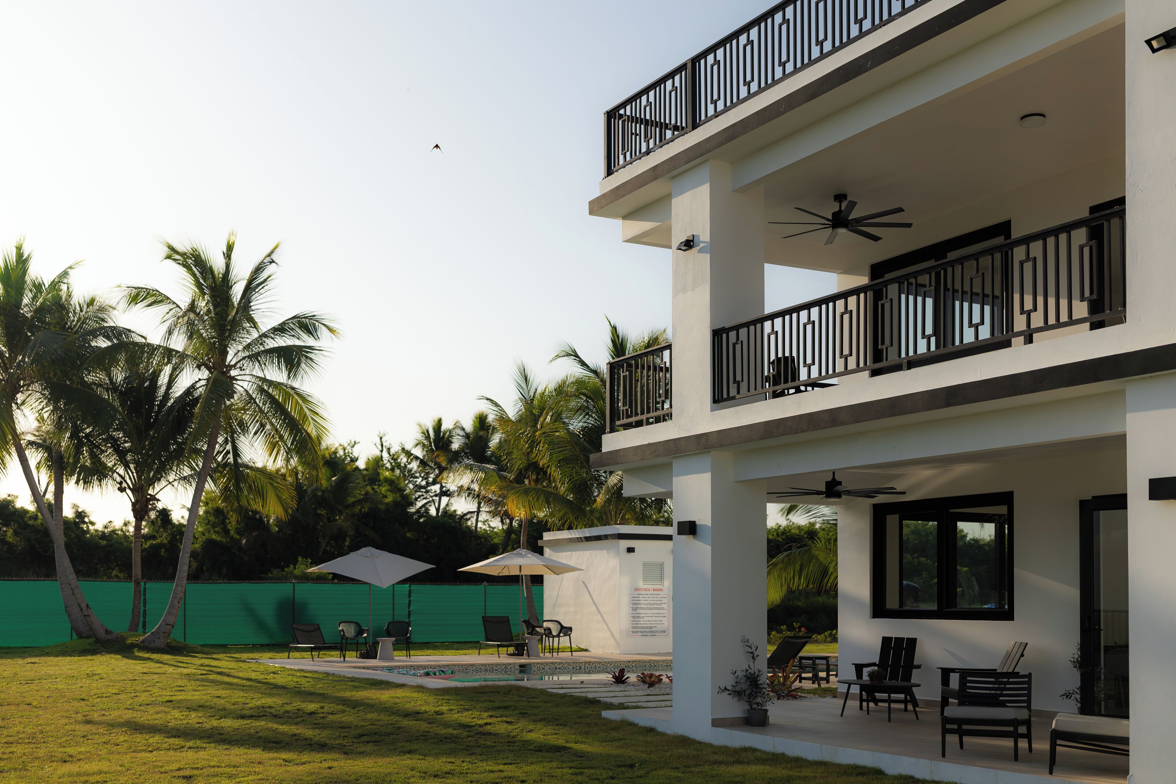 A two-story building with a balcony, outdoor seating, and a pool.