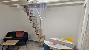 Une pièce comprenant un escalier, un canapé, une table basse et une table à manger avec des chaises.