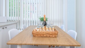 Ein Esstisch mit einer Champagnerflasche, Gläsern und einem Brotkorb.