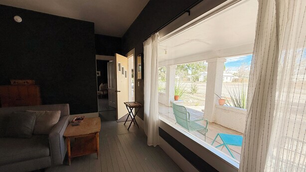 Ein Wohnzimmer mit einer Couch, einem kleinen Tisch und einem Fenster mit Blick ins Freie.