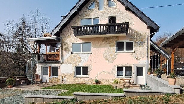 A multi-story house with a balcony, a staircase, and a driveway. - Cozy, newly renovated vacation apartment "Merlin" in the heart of the Taunus! (Weilrod)