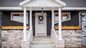 A house with a front porch, stone steps, and a number '5724' above the door.