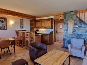 Un interior acogedor con un comedor de madera, una cocina con detalles de piedra y un espacio de estar confortable.