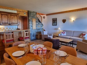Una sala acogedora con comedor, muebles de madera y una pared de piedra.