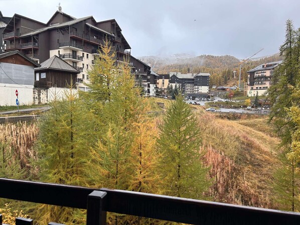 A mountain resort with multi-story buildings, a ski lift, and a view of the surrounding forest and mountains.