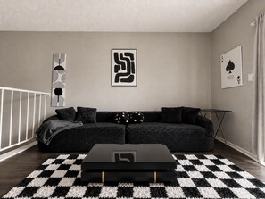Un salon moderne avec un tapis à carreaux noirs et blancs, un canapé noir et une table basse noire.
