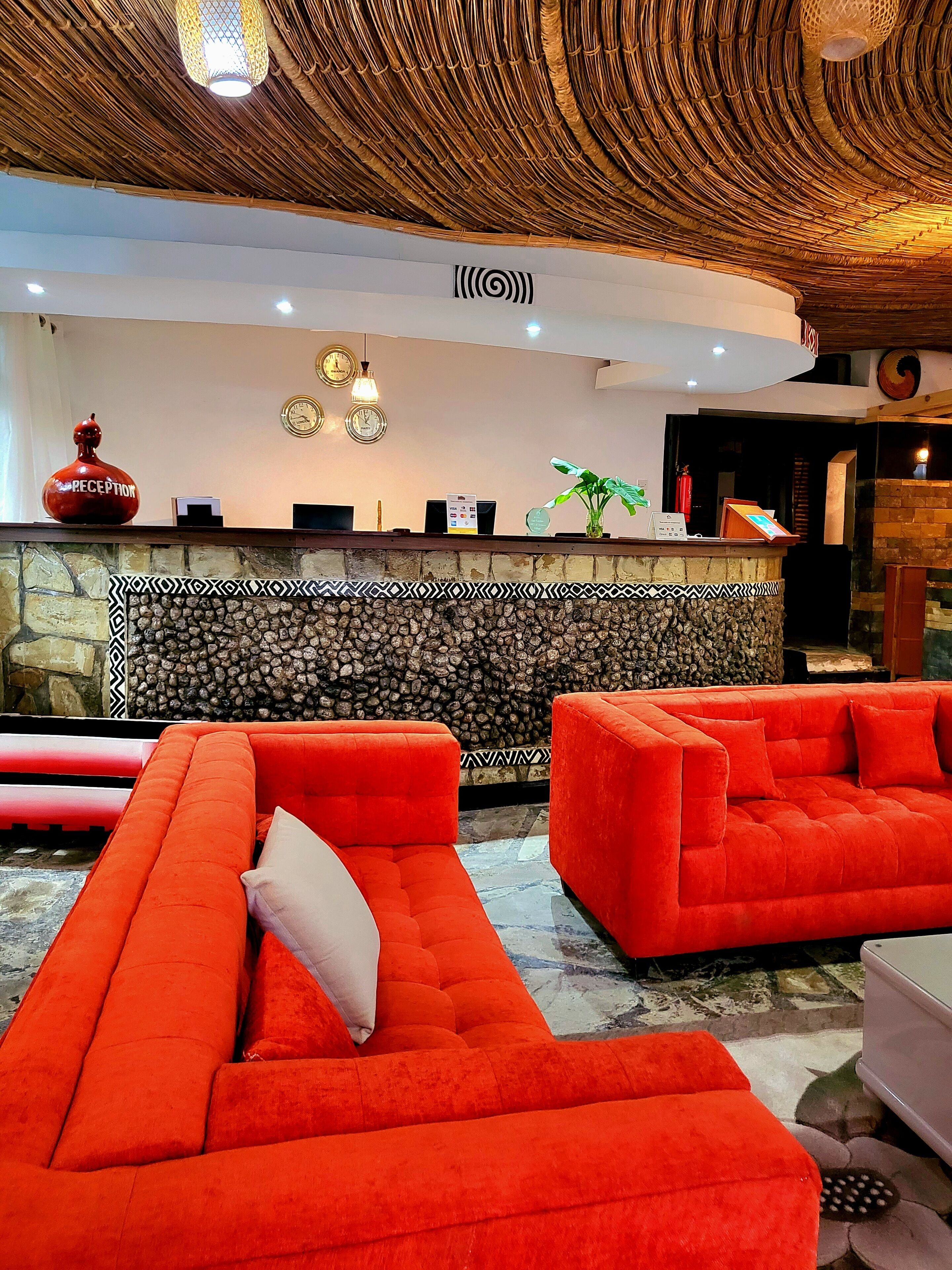 Uma área de recepção com parede de pedra, balcão e um sofá vermelho.