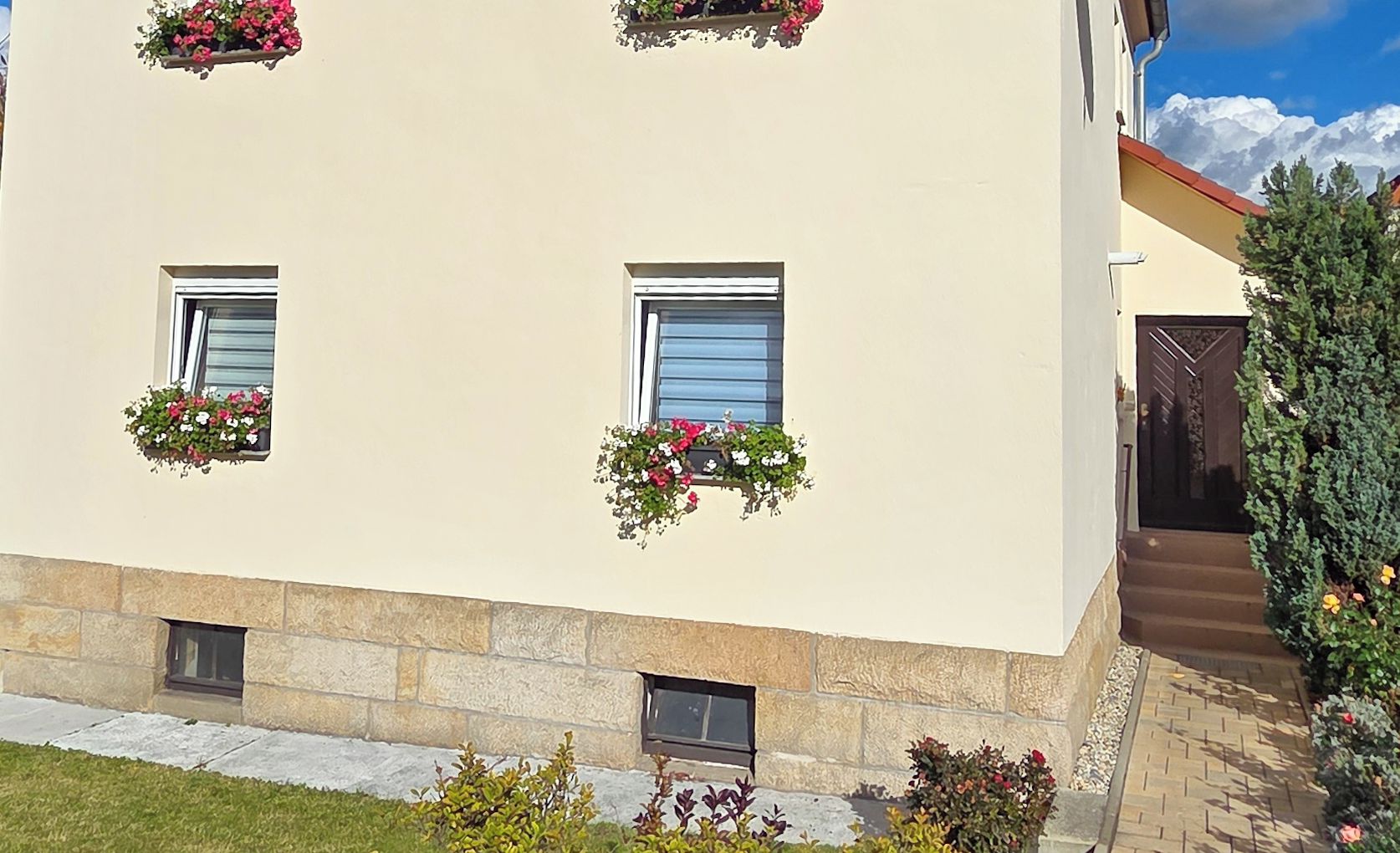 A building with multiple windows, some with flower boxes, and a stone base.