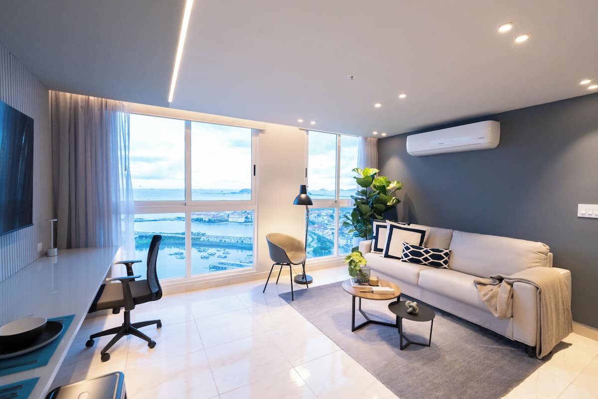 Una sala de estar moderna con un ventanal grande, un sofá, una mesa de centro, una silla y un escritorio.