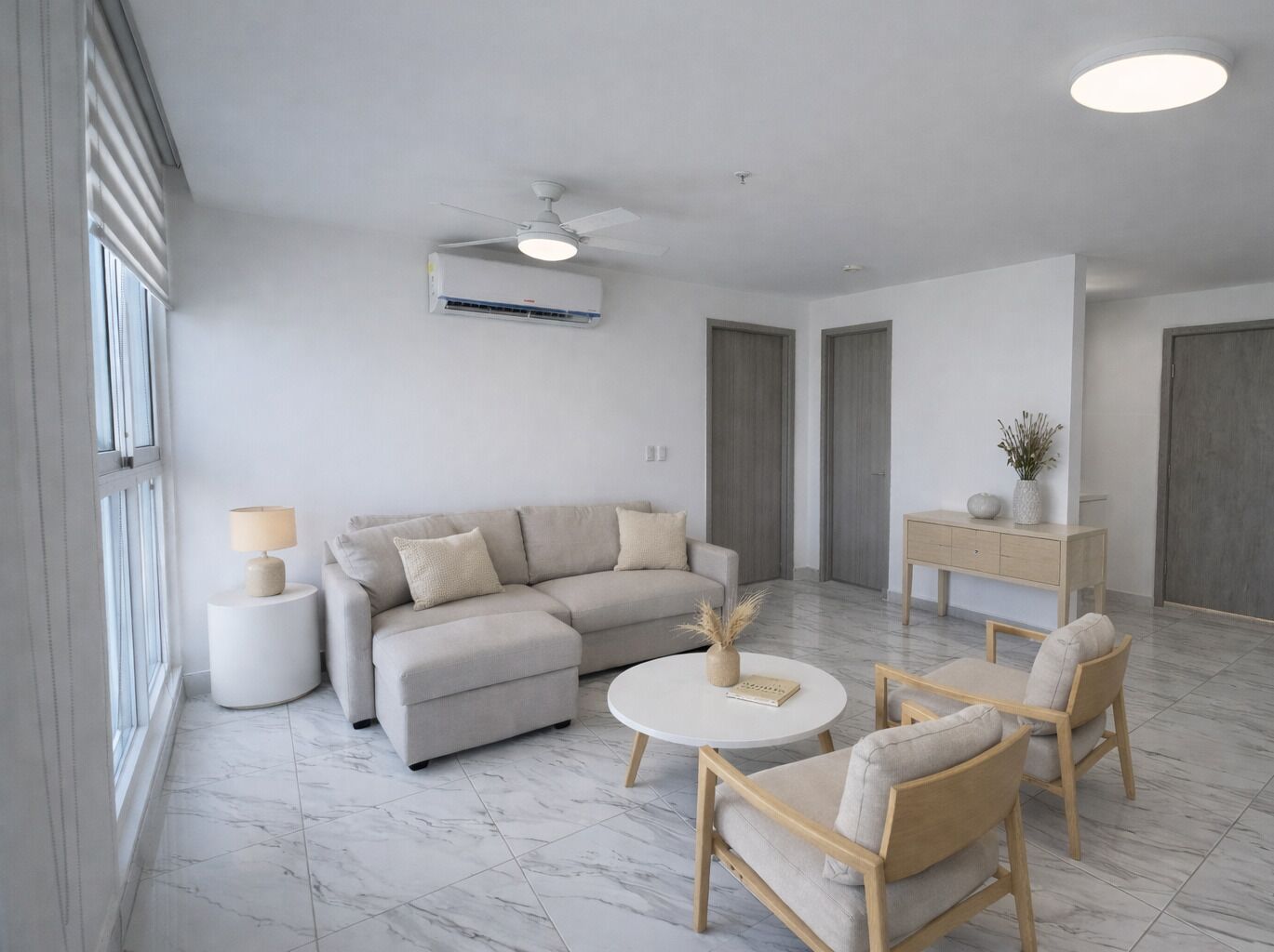 A modern living room with a sofa, two armchairs, a coffee table, a lamp, a side table, a ceiling fan, an air conditioning unit, and a cabinet.