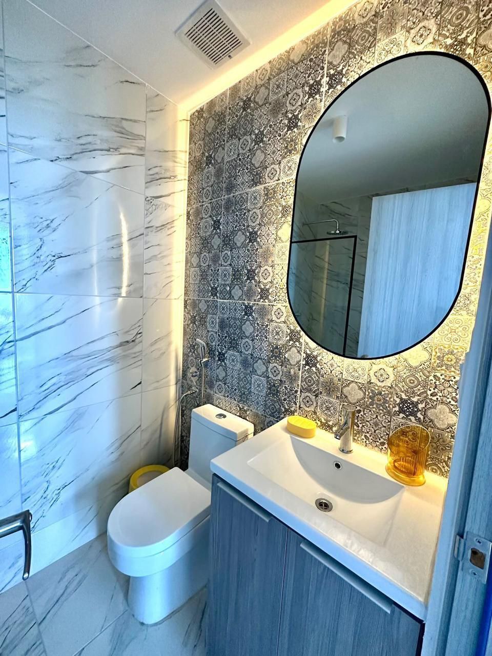 Et badeværelse med toilet, vask og spejl.