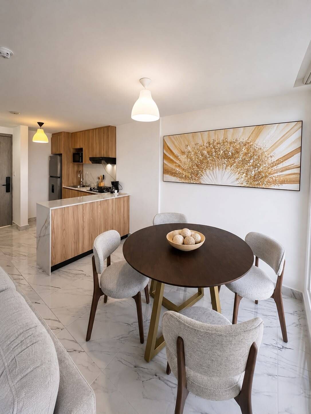 Una cocina moderna con armarios de madera, una isla central y un comedor con una mesa redonda y cuatro sillas.