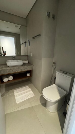 Un baño moderno con lavamanos, espejo, inodoro y ducha.