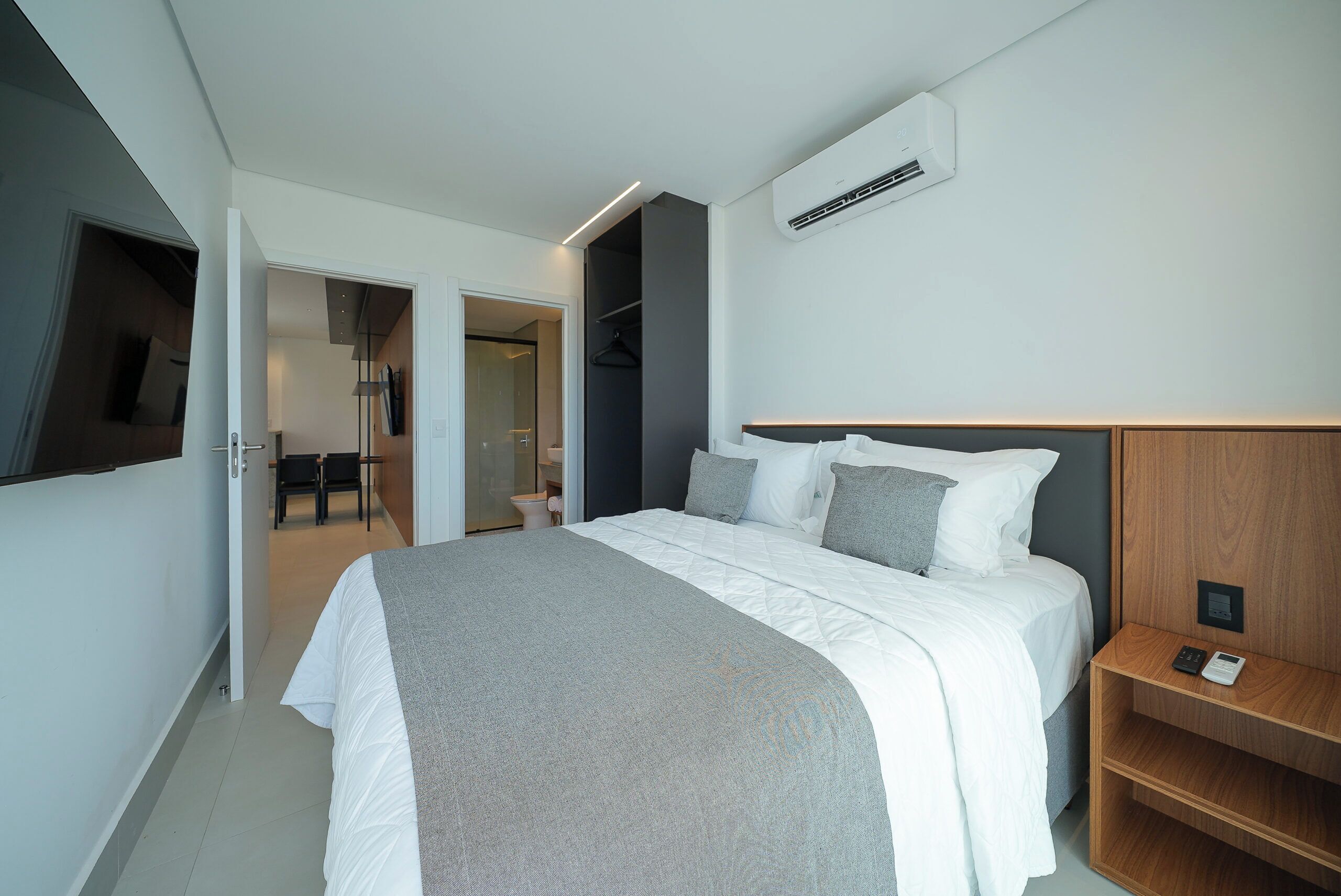 Una habitación de hotel moderna con una cama grande, mesitas de noche, un armario y un equipo de aire acondicionado.