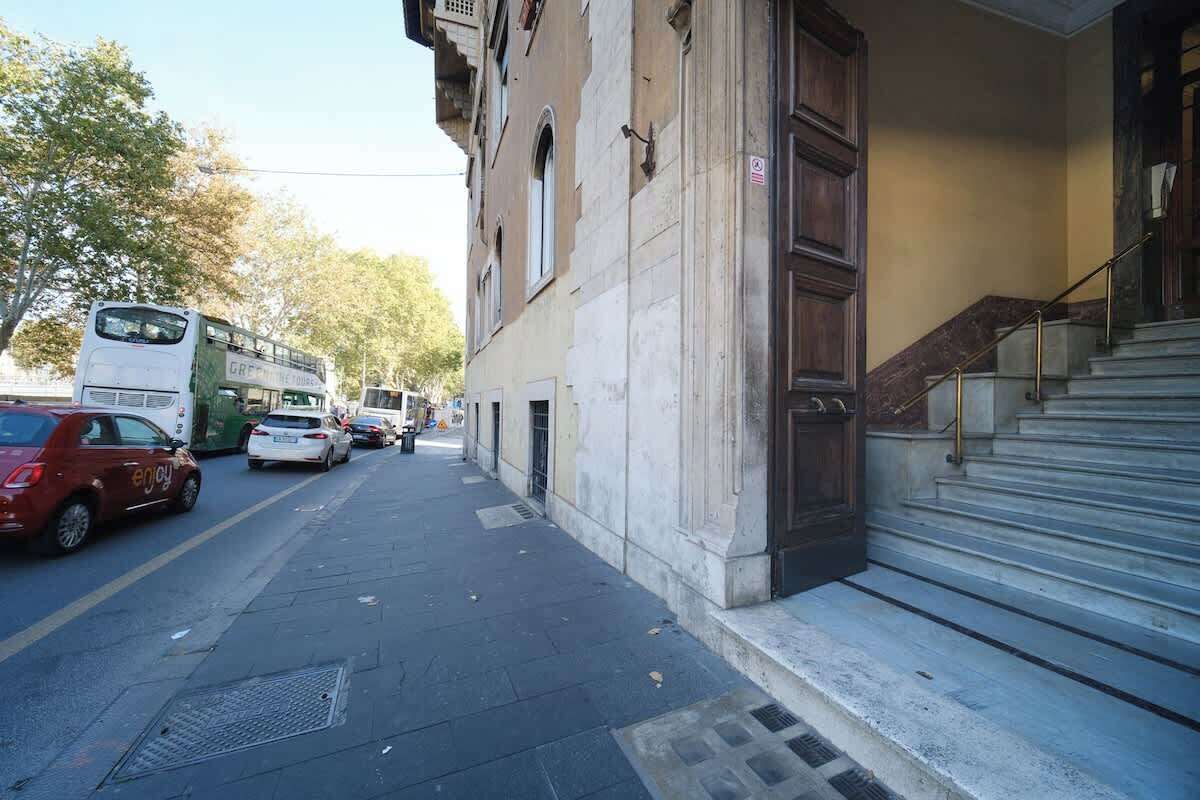 Une rue où l’on voit un autobus à deux étages, des voitures et un immeuble avec un escalier.