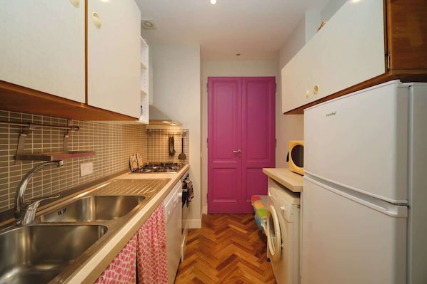 A compact kitchen with a sink, stove, and a washing machine.