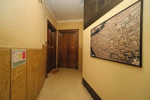 A hallway with wooden doors, a map on the wall, and a sign on the left.