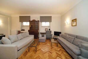 A living room with a sofa, armchair, ottoman, and a wooden cabinet.