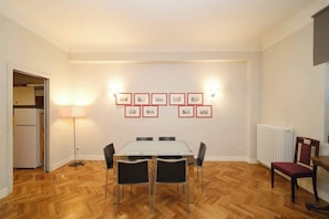 A dining area with a table and chairs, a radiator, and framed pictures on the wall.