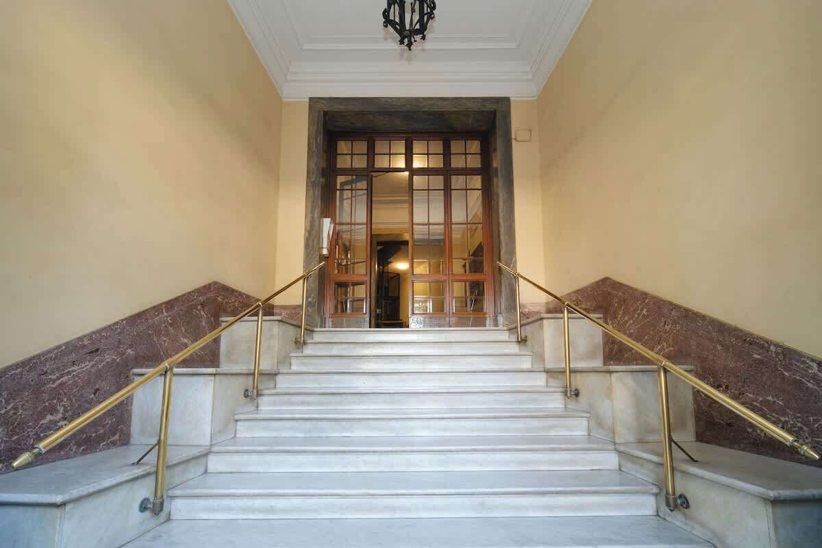 A marble staircase with handrails leading to a doorway.