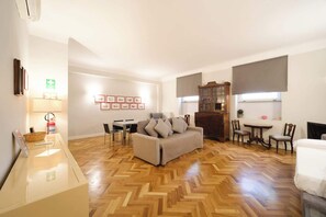 A well-lit living room with a herringbone floor, a sofa, a dining table, and a cabinet. - BuddyRent - Castel Sant'Angelo - 7 ospiti (Rome)