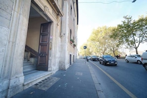 A street with parked cars, a building with a large door, and a sidewalk.