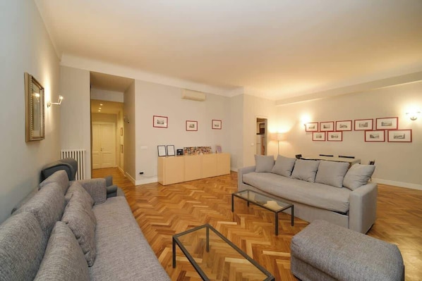 A living room with a sofa set, a coffee table, and a cabinet with framed pictures.