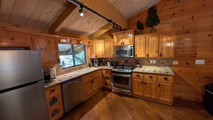 A kitchen with wooden cabinets, stainless steel appliances, and a window with a view of greenery.