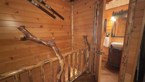 A wooden staircase with a rustic design, leading to a bathroom with a sink and mirror.