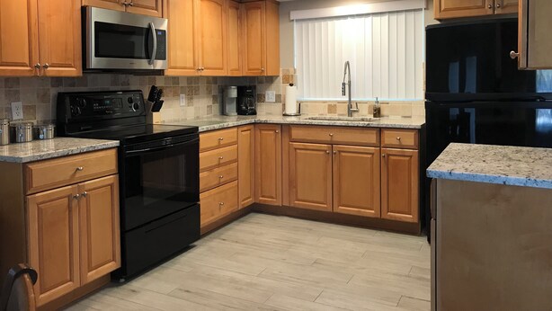 Una cucina moderna con mobili in legno, elettrodomestici in acciaio inossidabile e un lucernario.