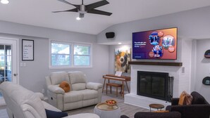 Una sala de estar moderna con chimenea, un televisor de pantalla plana montado arriba y un ventilador de techo.