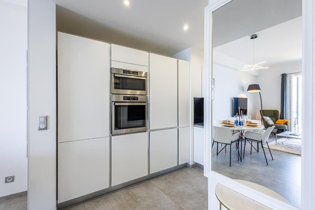 A modern kitchen with built-in ovens and a dining area with a table and chairs.