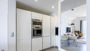 A modern kitchen with built-in ovens and a dining area with a table and chairs.