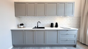 A kitchen with grey cabinets, a white countertop, a black faucet, and a coffee maker.