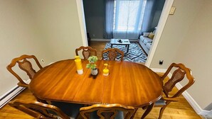 A dining table with six chairs, a vase with a plant, and candles. - The Grand Estate- 4 Bedroom  (Moncton)