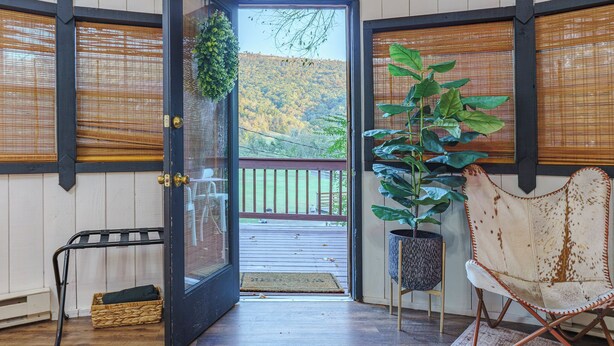 A room with a wooden floor, a black door leading to a balcony, a wicker basket, and a potted plant. - Adventurer Yurt - Landing Zone, Studio. Full Bathroom. Kitchenette. Updated. (Wildwood)