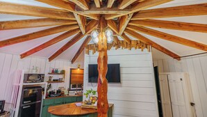 A kitchen with wooden beams, a central wooden column, and a built-in stove. - Adventurer Yurt - Landing Zone, Studio. Full Bathroom. Kitchenette. Updated. (Wildwood)