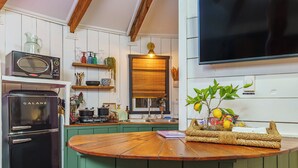 A kitchen with a Galanz microwave, a sink, a wooden countertop, and a television mounted on the wall. - Adventurer Yurt - Landing Zone, Studio. Full Bathroom. Kitchenette. Updated. (Wildwood)