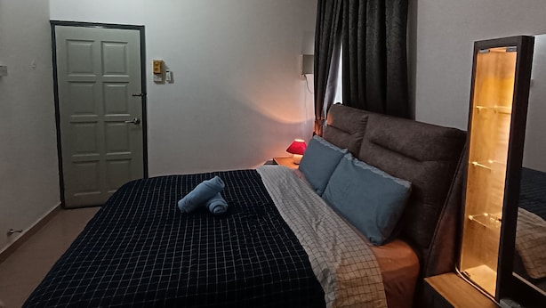 Ein Schlafzimmer mit einem Bett, einem Nachttisch mit Lampe, einem Spiegel und einer Tür.