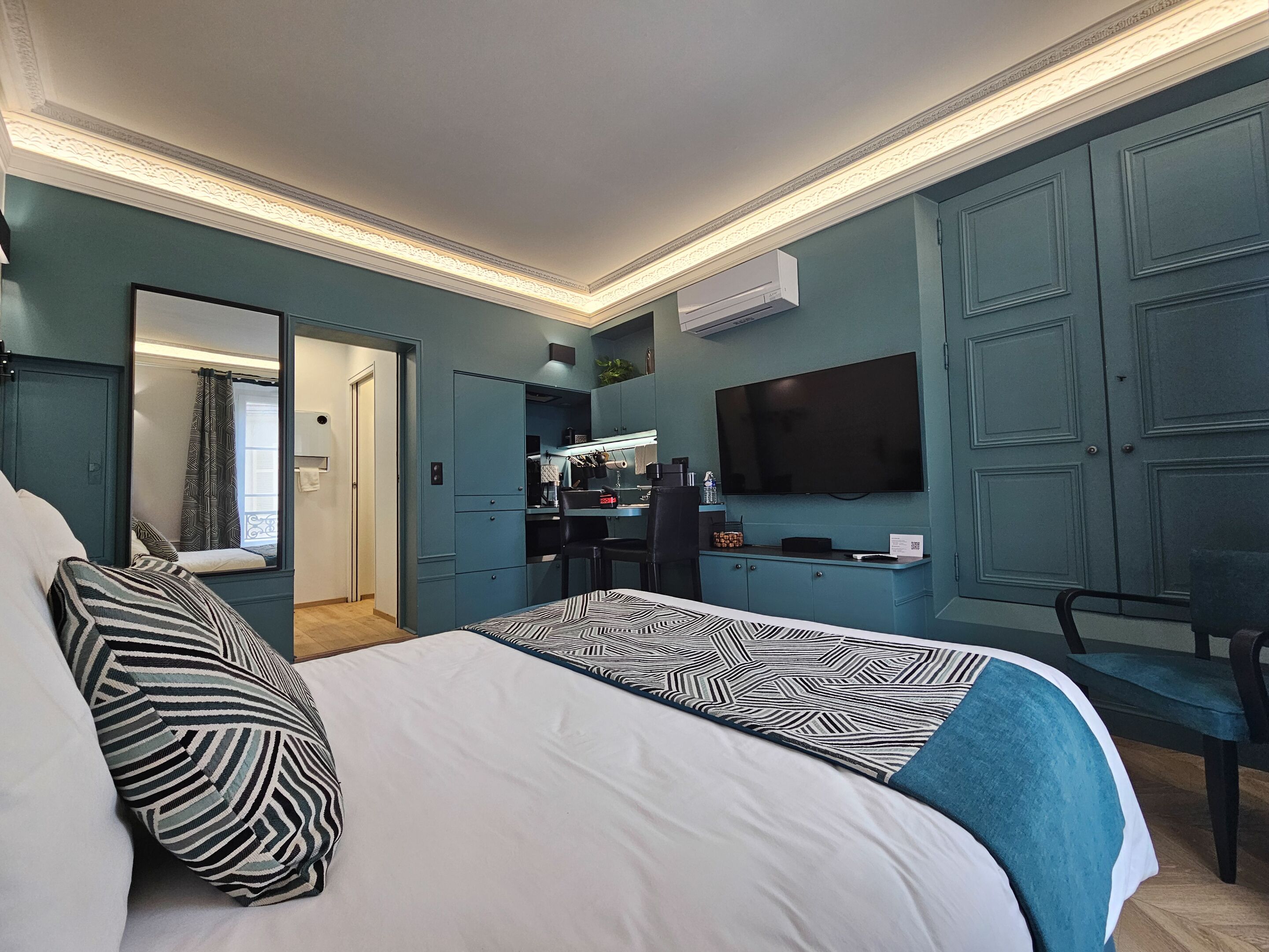 Una camera da letto moderna con un letto grande, una TV a muro e una cabina armadio.