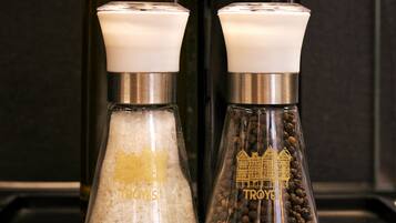 Deux salières et deux poivrières de la marque « Troyes », posées sur un comptoir noir.