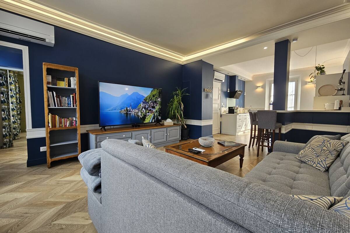 A modern living room with a large flat-screen TV, a bookshelf, a sofa, and a coffee table.