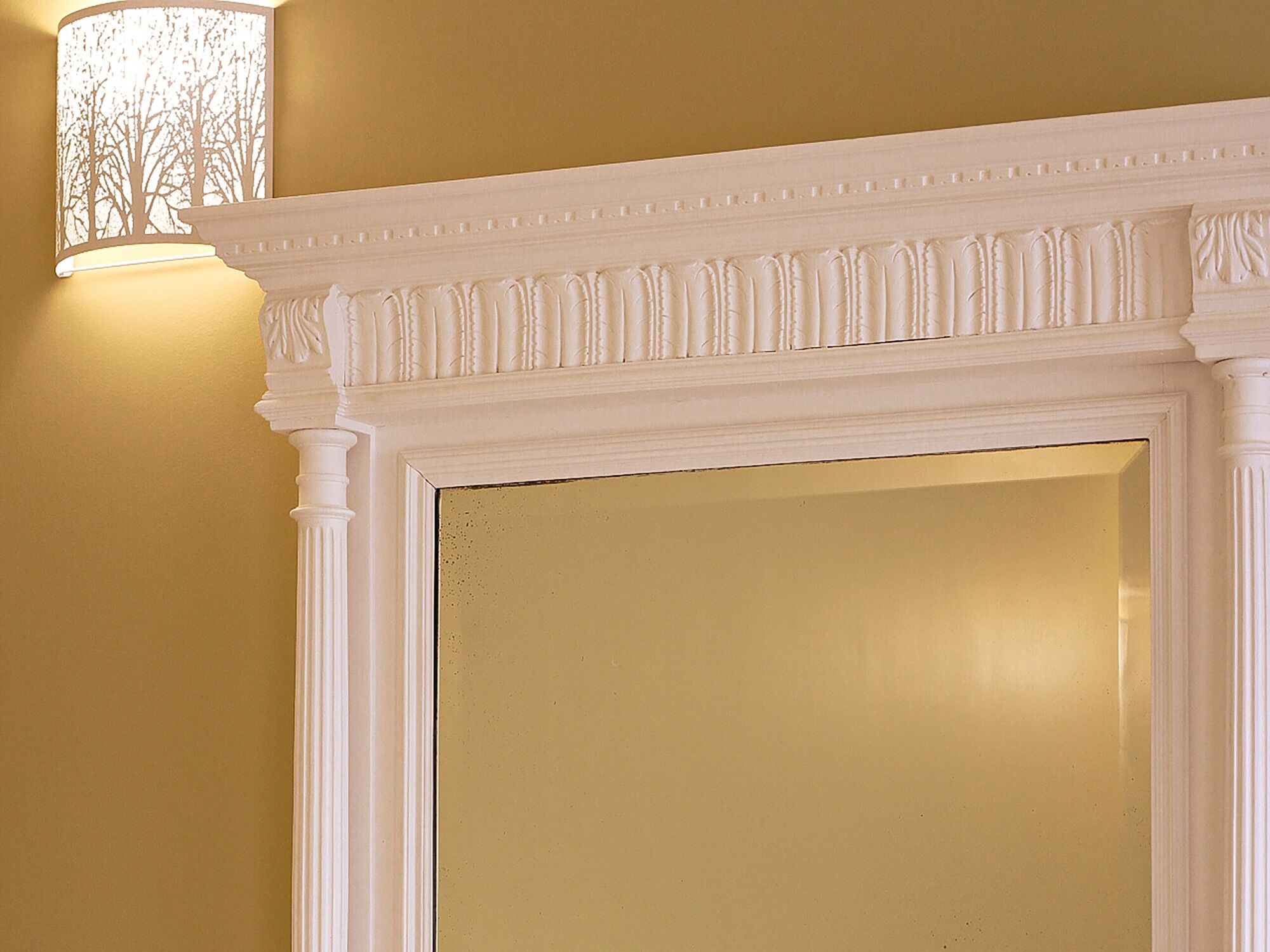 A white fireplace with a decorative mantel and a wall-mounted light fixture.