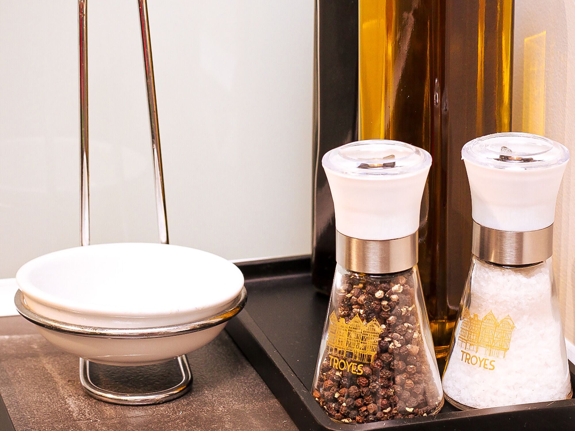 A kitchen counter with a white bowl, two salt and pepper shakers, and a bottle of oil.