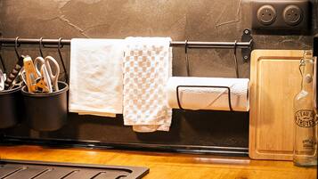 A kitchen with a black countertop, a cutting board, a bottle of water, and a towel rack with towels.