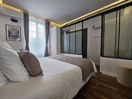 Un dormitorio moderno con una cama grande, un vestidor amplio y un ventanal con cortinas.