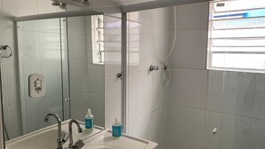 A bathroom with a sink, mirror, and shower.